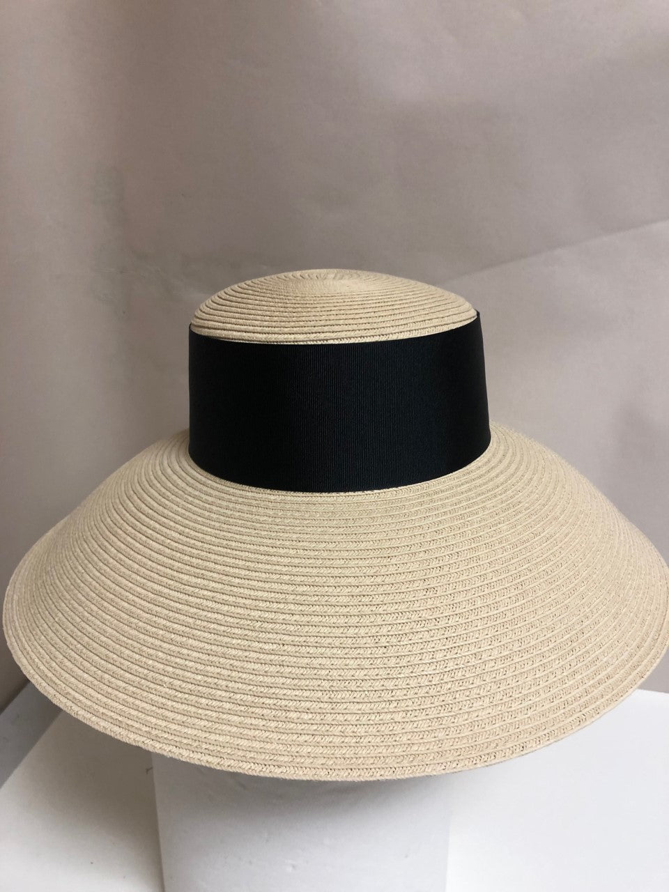 straw hat with a thick black trim around the crown and a wide, sloping brim 